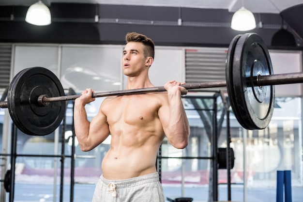 Fit man lifting barbell at gym