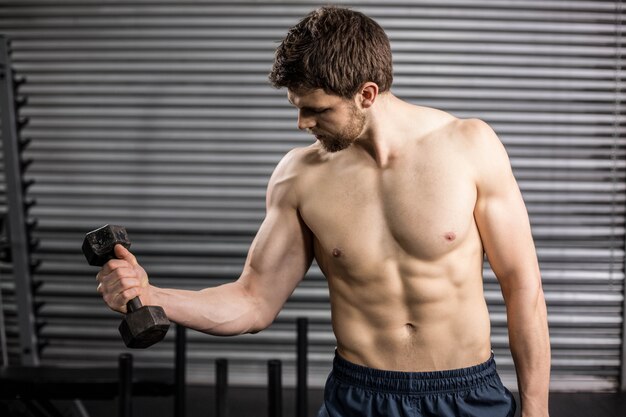 Fit man lifting dumbbells at crossfit gym