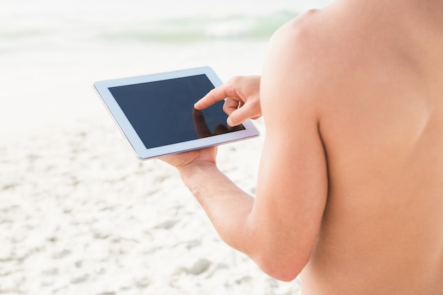 Fit man met behulp van tablet op het strand