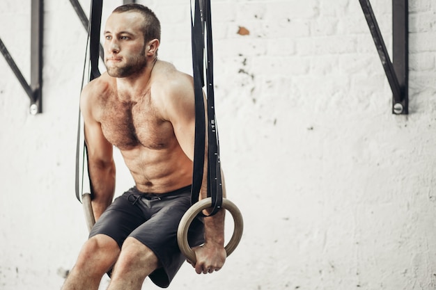 Fit man optrekken op gymnastische ringen.