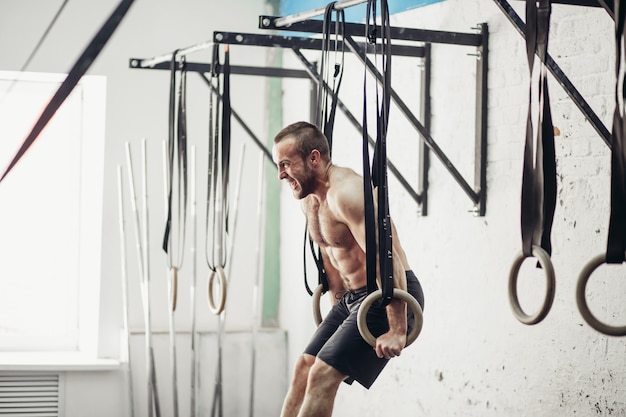 Fit man optrekken op gymnastische ringen.