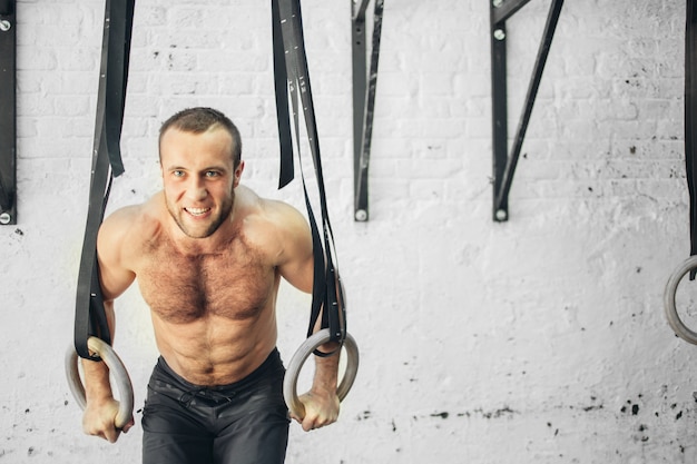 Fit man optrekken op gymnastische ringen.