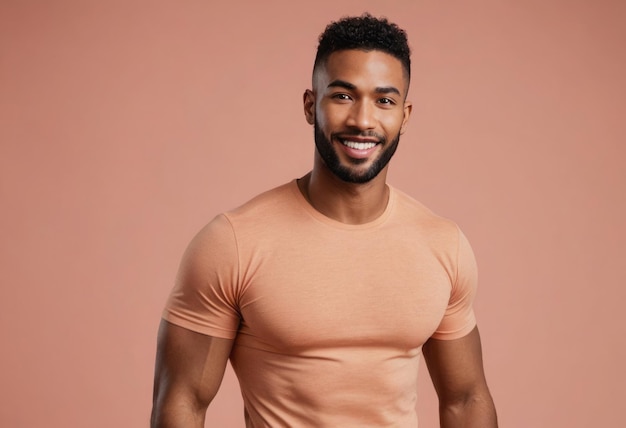 A fit man poses confidently in a peach tshirt the background is a matching warm hue