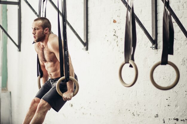 Fit man pulling up on gymnastic rings.