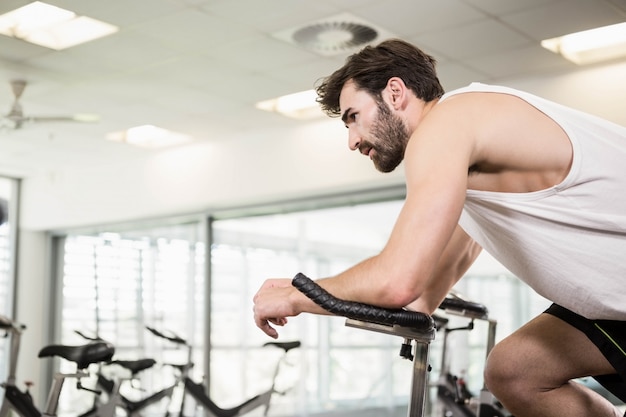 Fit man using exercise bike at the gym