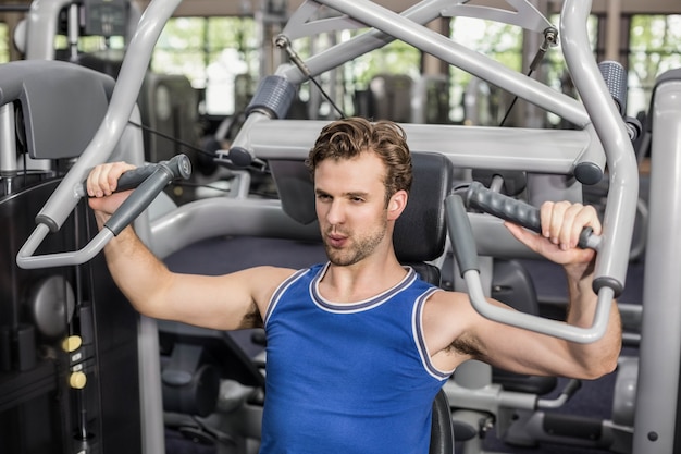 Fit man using weight machine at gym