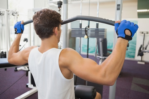 Fit man using weights machine for arms