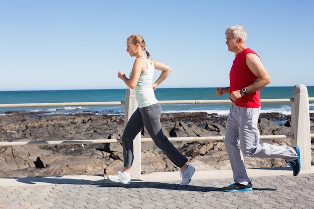 Fit mature couple jogging together on the pier