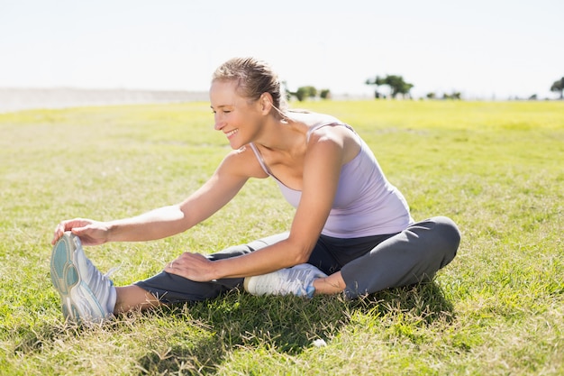 Fit mature woman warming up on the grass