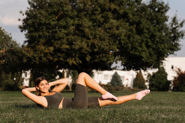 Fit meisje training op groen gras in het park Outdoor workout Sport levensstijl van actieve jonge vrouw