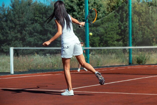 Fit mommy wearing white shorts playing tennis with daughter