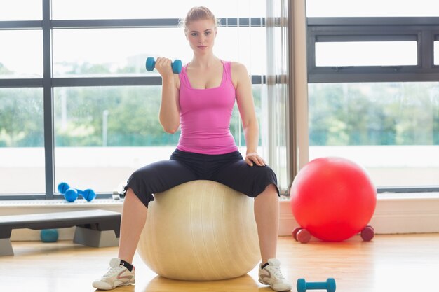 Fit mooie vrouw met dumbbell zittend op oefening bal