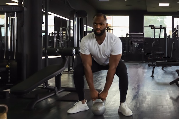 L'uomo africano in forma e muscoloso si è concentrato sul sollevamento di un manubrio durante una lezione di ginnastica in palestra