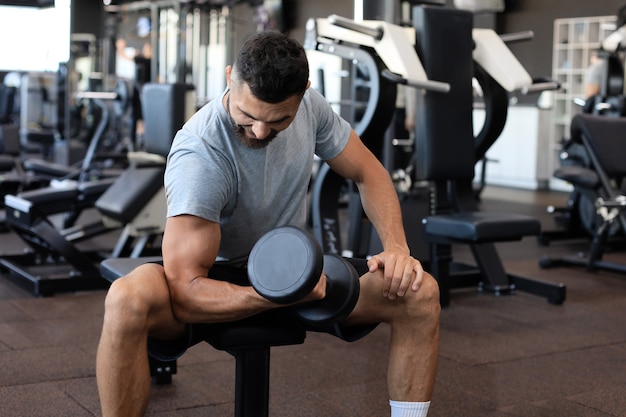 Fit and muscular indian man trains with dumbbells.