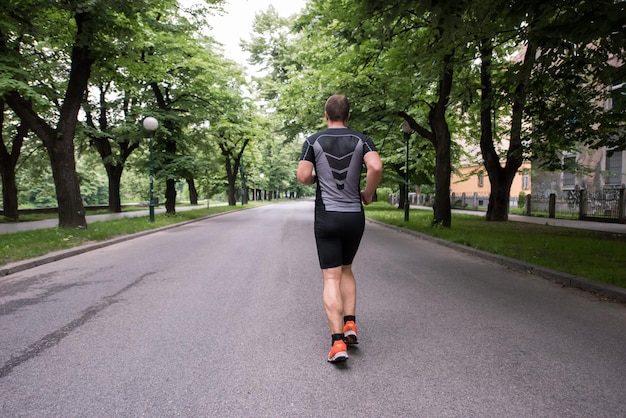 자연의 아름다운 도로에서 달리는 마라톤을위한 근육질 남성 러너 훈련에 적합합니다.