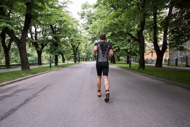 自然の中で美しい道を走るマラソンのための筋肉質の男性ランナートレーニングに合う。