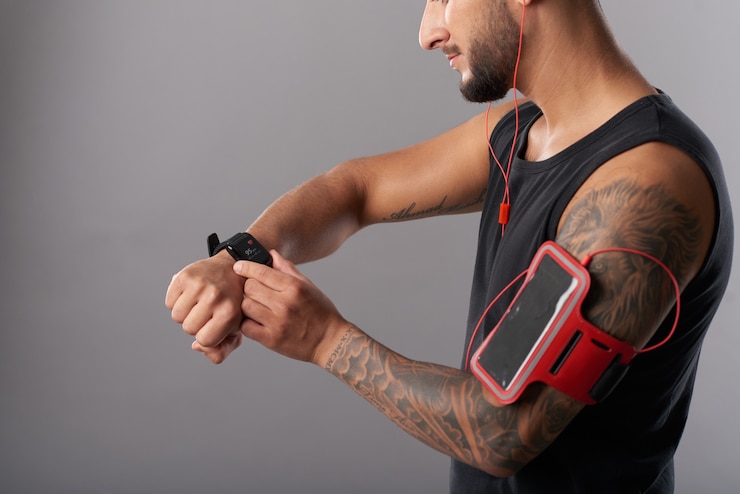 Fit muscular man checking fitness trekker on smartwatch after jogging in the morning