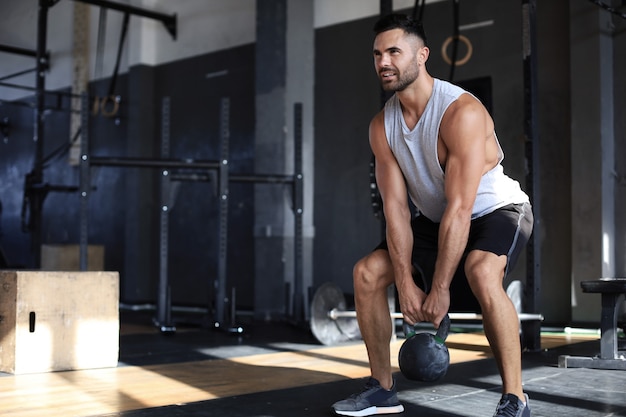 Fit and muscular man focused on lifting a dumbbell during an exercise class in a gym.