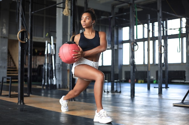 ジムで薬のボールで運動している健康で筋肉質の女性。