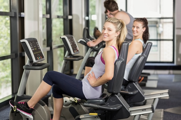 Fit people doing exercise bike at gym