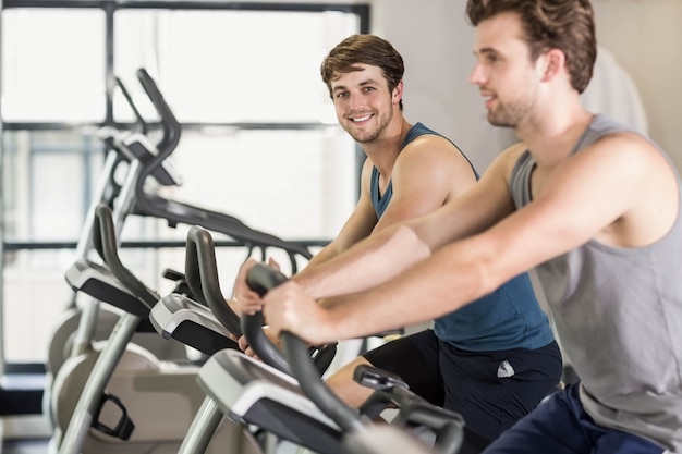 Fit people doing exercise bike at gym