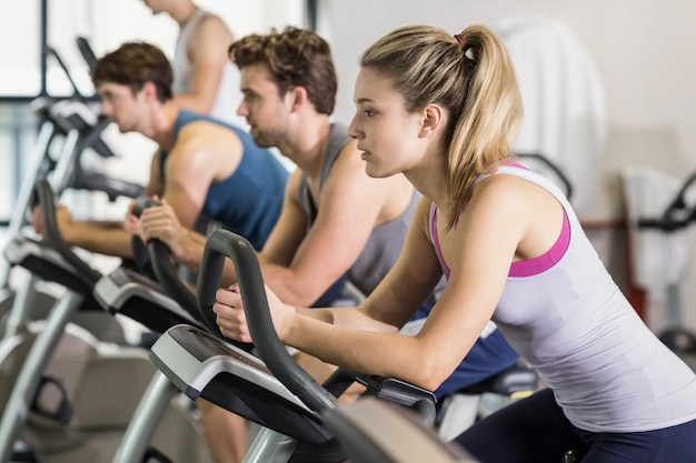 Fit people doing exercise bike at gym