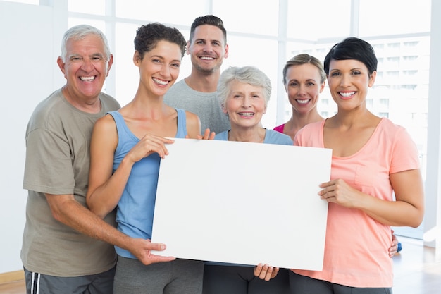 Fit people holding blank board in yoga class