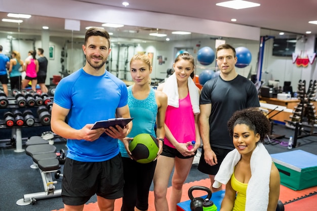 Fit people smiling at camera in weights room