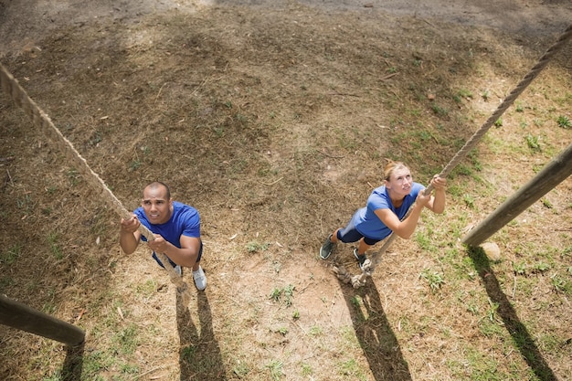 Fit person climbing down the rope during obstacle course in boot camp