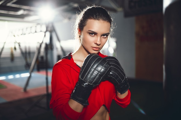 Fit slanke jonge mooie brunette vrouw boksen in sportkleding. Donker zwak licht.