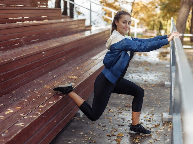 Fit slanke vrouw oefent het uitrekken van het been. Buitentraining. Gezond levensstijlconcept