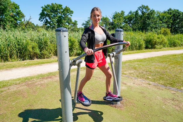 fit slim girl making exercises on a playground outdoor sport street gym