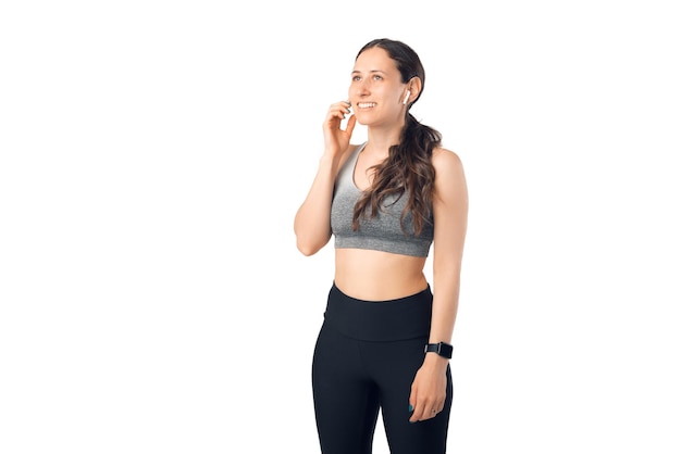 Fit smiling girl is using her ear pods while practicing sports.