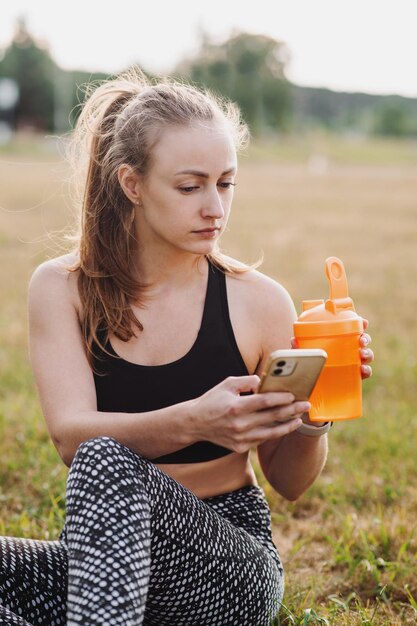 Fit sportieve vrouw met waterfles ontspannen na trainingen buiten