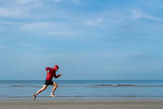 ビーチで実行されているフィットの陽気な若い男