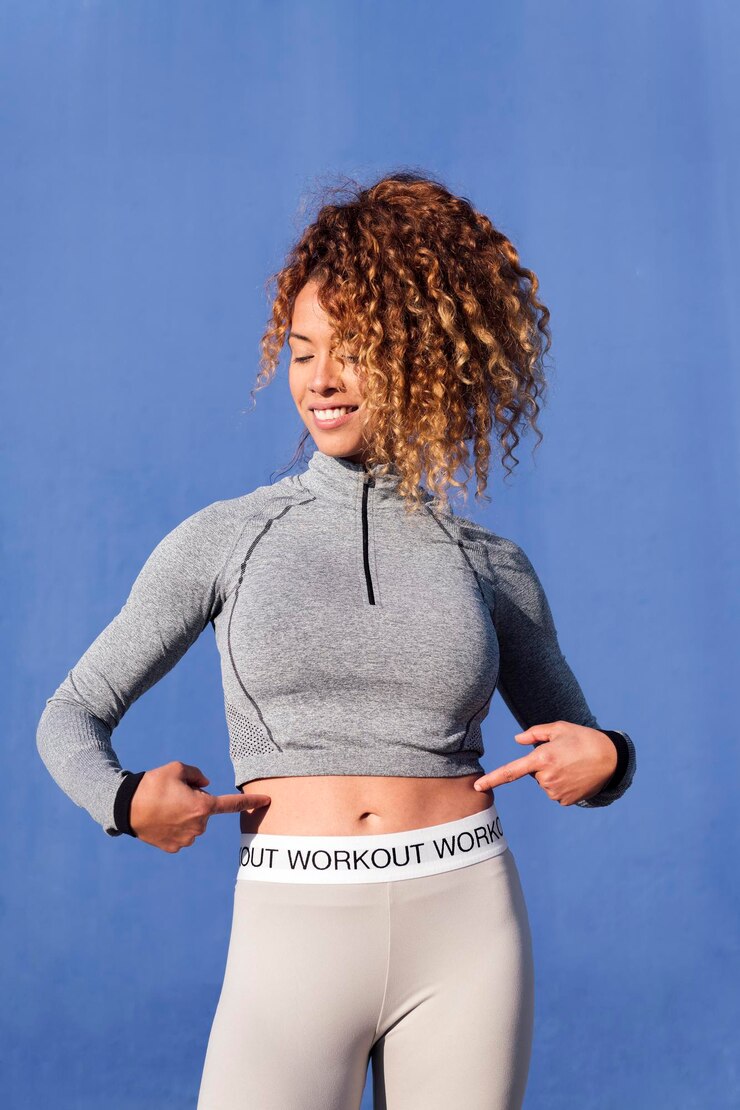 Photo fit sports woman pointing her flat stomach