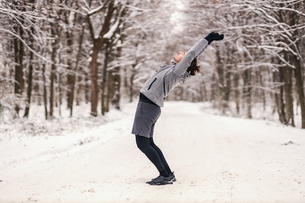 숲에서 눈 덮인 겨울 날에 워밍업 운동을하는 스포츠맨을 맞추십시오. 겨울 피트니스, 건강한 삶