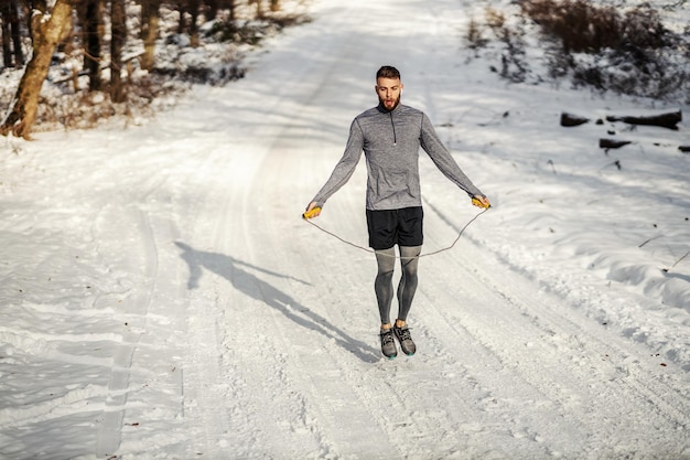 Fit sportsman jumping the rope in woods at snowy winter day
winter fitness cardio exercises