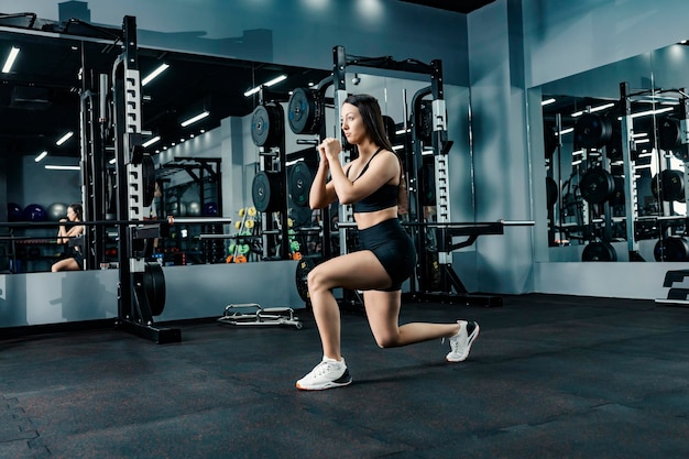 A fit sportswoman does stretching and fitness exercises in a gym