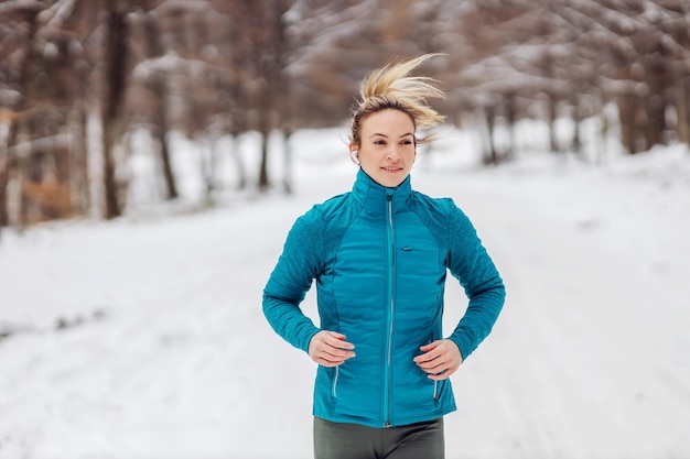 Fit sportswoman running in nature on a snowy weather cold\
weather snow healthy life fitness