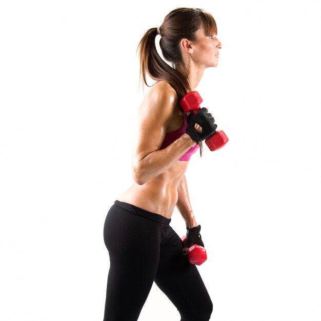 Fit and sporty young woman lifting dumbbells over white background.