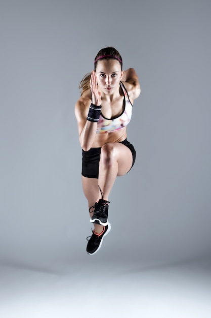 Fit and sporty young woman running on white background.