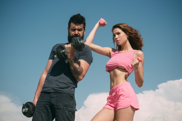 Fit and strong. Sensual fit woman and bearded man doing sport exercises. Athletic woman and strong hipster keeping bodies fit with dumbbell workout. Sexy couple of athletes feeling fit and healthy.