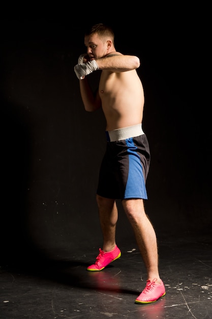 Fit strong young boxer working out in the ring