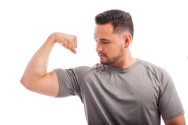 Foto giovane in forma e forte che flette il braccio e mostra i suoi muscoli su uno sfondo bianco