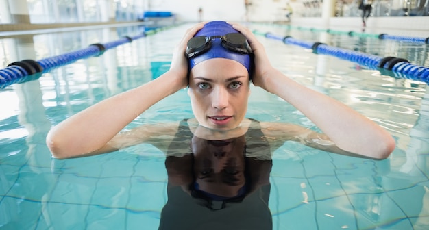 Fit swimmer in the pool smiling at camera at the leisure center