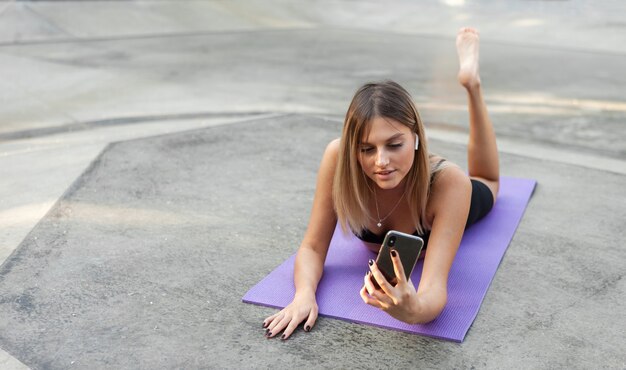 Fit vrouw die buiten rust na de training en smartphone gebruikt