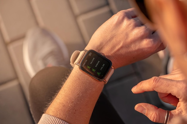 Fit vrouw die slimme horloge wearable technologie controleert, sport smartwatch op fitness loop buiten. Bovenaanzicht van bovenaf met hardloopschoenen in de straat.