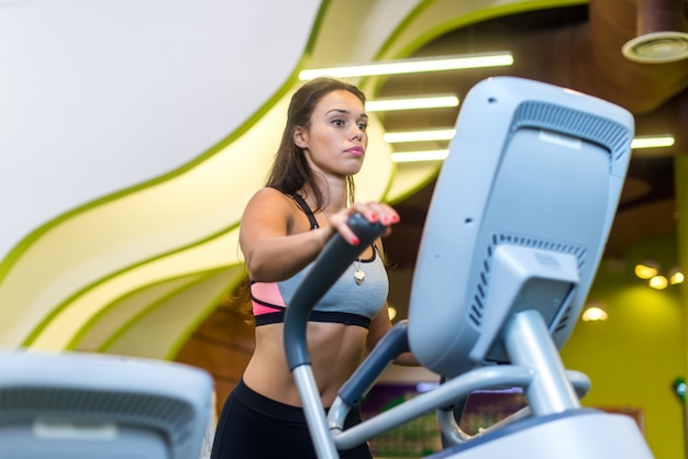 Fit vrouw doet cardio in een elliptische trainer in een sportschool.