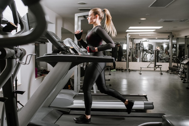 Fit vrouw draait op de loopband in de sportschool